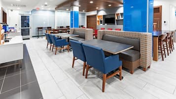 A modern restaurant with booths and tables, a counter, and a TV mounted on the wall.