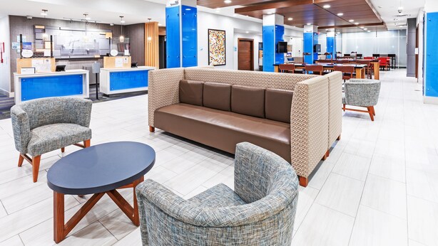 A modern lobby with a reception desk, seating area, and dining space.