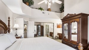 Ein Schlafzimmer mit einem großen Bett, einem Holzschrank und einem Deckenventilator.
