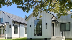 A modern two-story house with a large glass window, a concrete driveway, and a well-maintained lawn. - Luxury Executive Home located in the heart of the city (Coeur d'Alene)