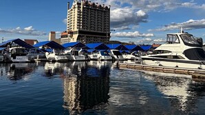 A marina with boats docked under blue canopies, a tall hotel building in the background, and a clear blue sky with scattered clouds. - Luxury Executive Home located in the heart of the city (Coeur d'Alene)