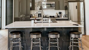 A modern kitchen with a large island, stainless steel appliances, and bar stools. - Luxury Executive Home located in the heart of the city (Coeur d'Alene)