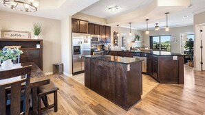 Una cocina amplia con armarios de madera oscura, una isla grande y una zona de comedor con mesa y sillas de madera.