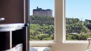 Una stanza con un'ampia finestra che offre vista su un edificio di un hotel e sulla vegetazione circostante.