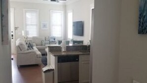 Une cuisine moderne avec des meubles blancs, un lave-vaisselle et un plan de travail. On y trouve également un coin repas avec une table et des chaises blanches.
