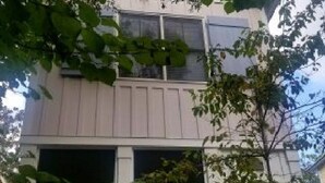 Un bâtiment à deux étages, doté d’une façade beige, de grandes fenêtres à l’étage supérieur et d’une entrée de garage au rez-de-chaussée.