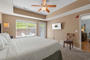 Une chambre dotée d’un grand lit, d’un ventilateur de plafond, d’une télévision et offrant une vue sur l’extérieur.