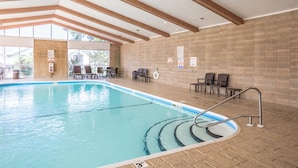 Ein Hallenbad mit klarem Wasser, Holzbalken an der Decke und einer gefliesten Wand.