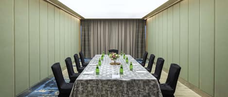 A conference room with a long table, chairs, and a floral centerpiece.