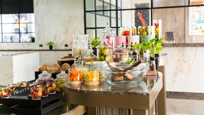 Een buffetopstelling met diverse gerechten en drankjes, waaronder fruit, salades en een selectie dranken.