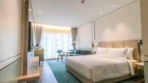 Een moderne hotelkamer met een groot bed, een bureau, een stoel en een bijzettafeltje.