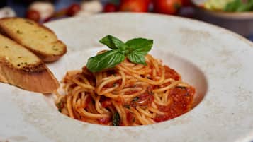 A plate of spaghetti with a basil leaf garnish, accompanied by toasted bread slices.
