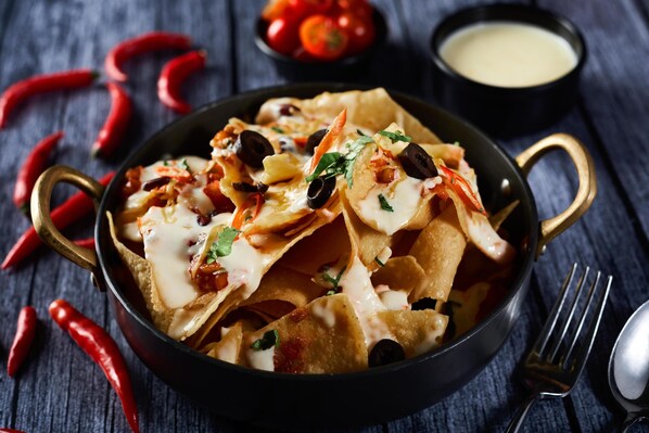 Nachos in a black skillet with red chili peppers and a small bowl of sauce. - Radisson Blu Mumbai International Airport (Mumbai)