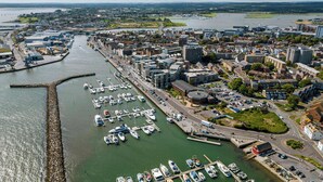 An aerial view of a marina with boats docked, surrounded by urban buildings and a river. - Reel Time - A Stone's Throw from Poole Quay (Poole)