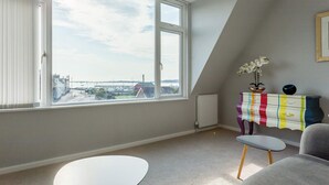 A room with a large window, a radiator, a colorful cabinet, and a small table. - Reel Time - A Stone's Throw from Poole Quay (Poole)