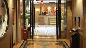 A hotel lobby with a reception desk, a large mirror, and a patterned floor. - Zhongfa Hotel (Linxiang)