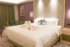 Una habitación de hotel con una cama grande, un sofá verde y una mesita de noche con una lámpara.