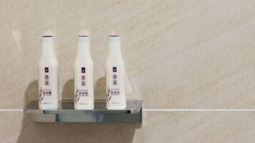 Three bottles of a product on a metallic shelf against a tiled wall.