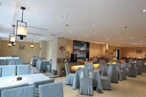 Un comedor de hotel con varias mesas y sillas, una recepción y un ventanal grande.