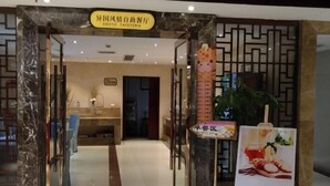 The entrance to a hotel with a reception desk, a decorative giraffe sculpture, and a poster advertising breakfast. - Zhongfa Hotel (Linxiang)