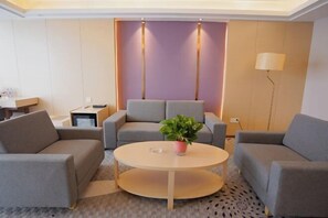 A modern living room with two sofas, a coffee table, and a potted plant. - Zhongfa Hotel (Linxiang)