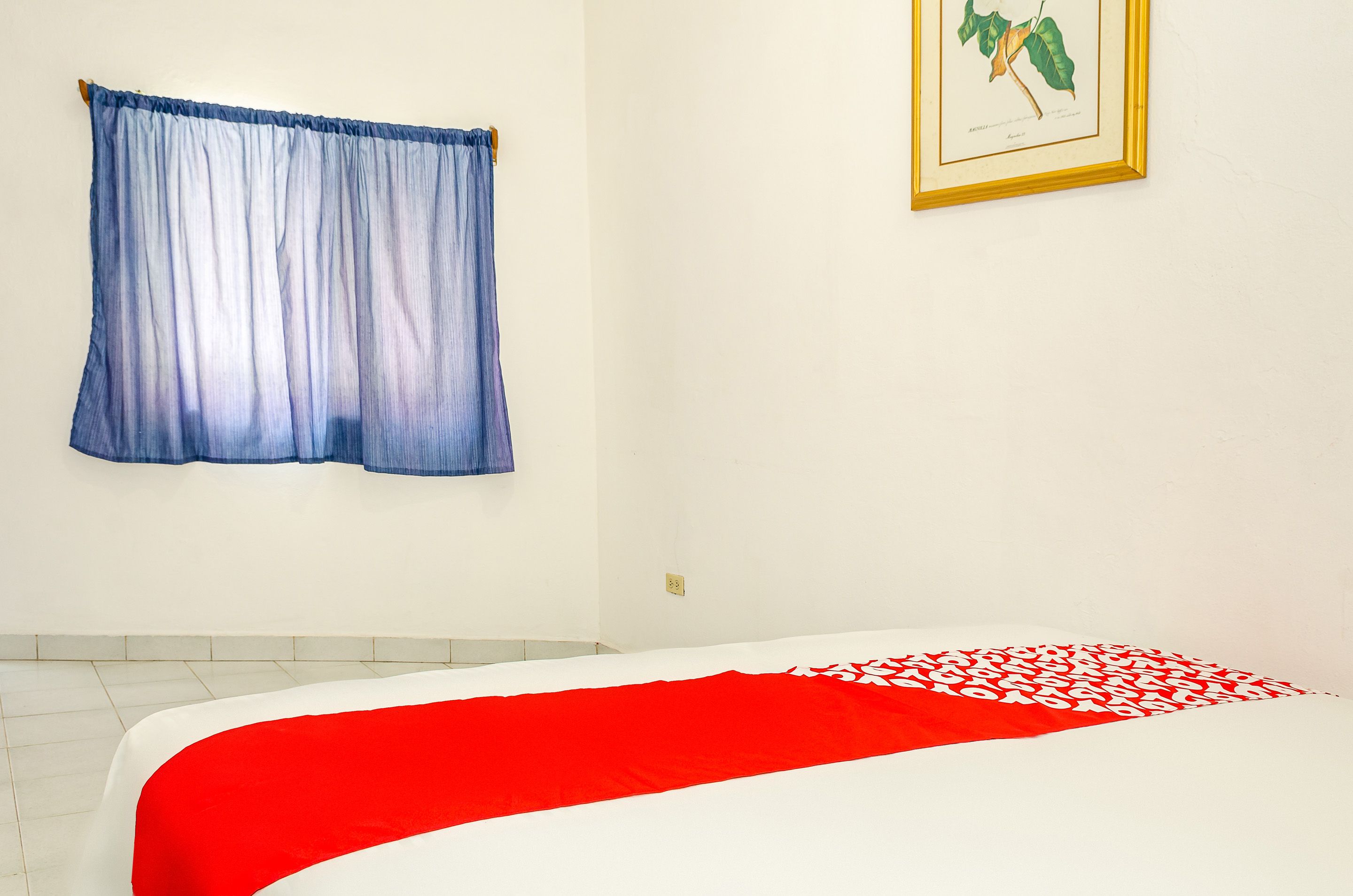 Un dormitorio con cama, ventana con cortinas e ilustración botánica enmarcada en la pared.