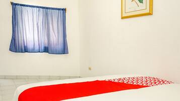 Un dormitorio con cama, ventana con cortinas e ilustración botánica enmarcada en la pared.