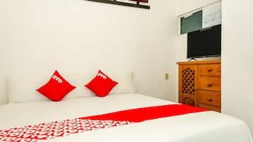 Un lit bien fait, recouvert d’une couvre-lit à motifs rouges et blancs, et agrémenté de deux oreillers rouges.