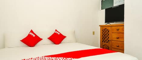 Una cama bien hecha con una colcha de diseño rojo y blanco y dos almohadas rojas.