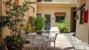 An outdoor patio with a table and chairs, surrounded by potted plants.