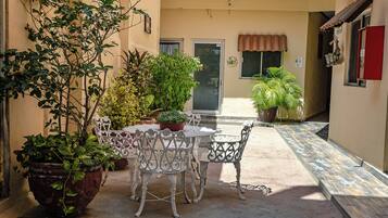An outdoor patio with a table and chairs, surrounded by potted plants.