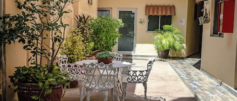 Une terrasse extérieure avec une table et des chaises, entourée de plantes en pot.