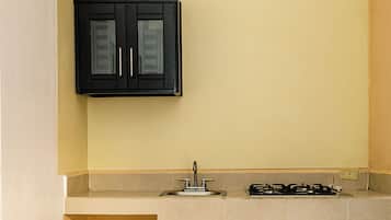 Eine Küche mit einem schwarzen Schrank über einer beige gefärbten Arbeitsplatte, einem Spülbecken und einem Gasherd.