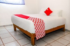 A bed with a white mattress, a red and white patterned blanket, and a red pillow.