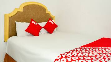 A bed with a wooden headboard, two red pillows, and a white bedspread.