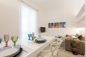 A modern living room with a dining area, white furniture, and artwork on the wall. - Palermoinsuite Aparthotel (Palermo)