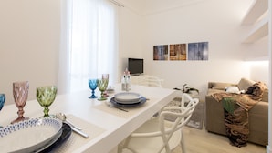 A modern living room with a dining area, white furniture, and artwork on the wall. - Palermoinsuite Aparthotel (Palermo)