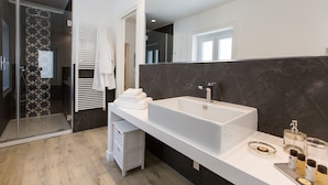 A modern bathroom with a large white sink, dark marble walls, and a glass shower enclosure. - Palermoinsuite Aparthotel (Palermo)