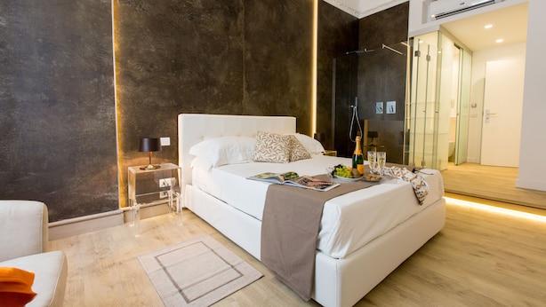 A modern bedroom with a large bed, bedside tables, a glass shower enclosure, and a mirror. - Palermoinsuite Aparthotel (Palermo)