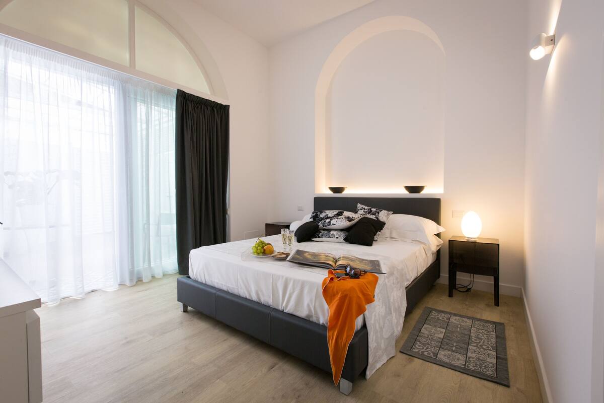 Ein modernes Schlafzimmer mit einem großen Bett, Nachttischen und einer Nachttischlampe.