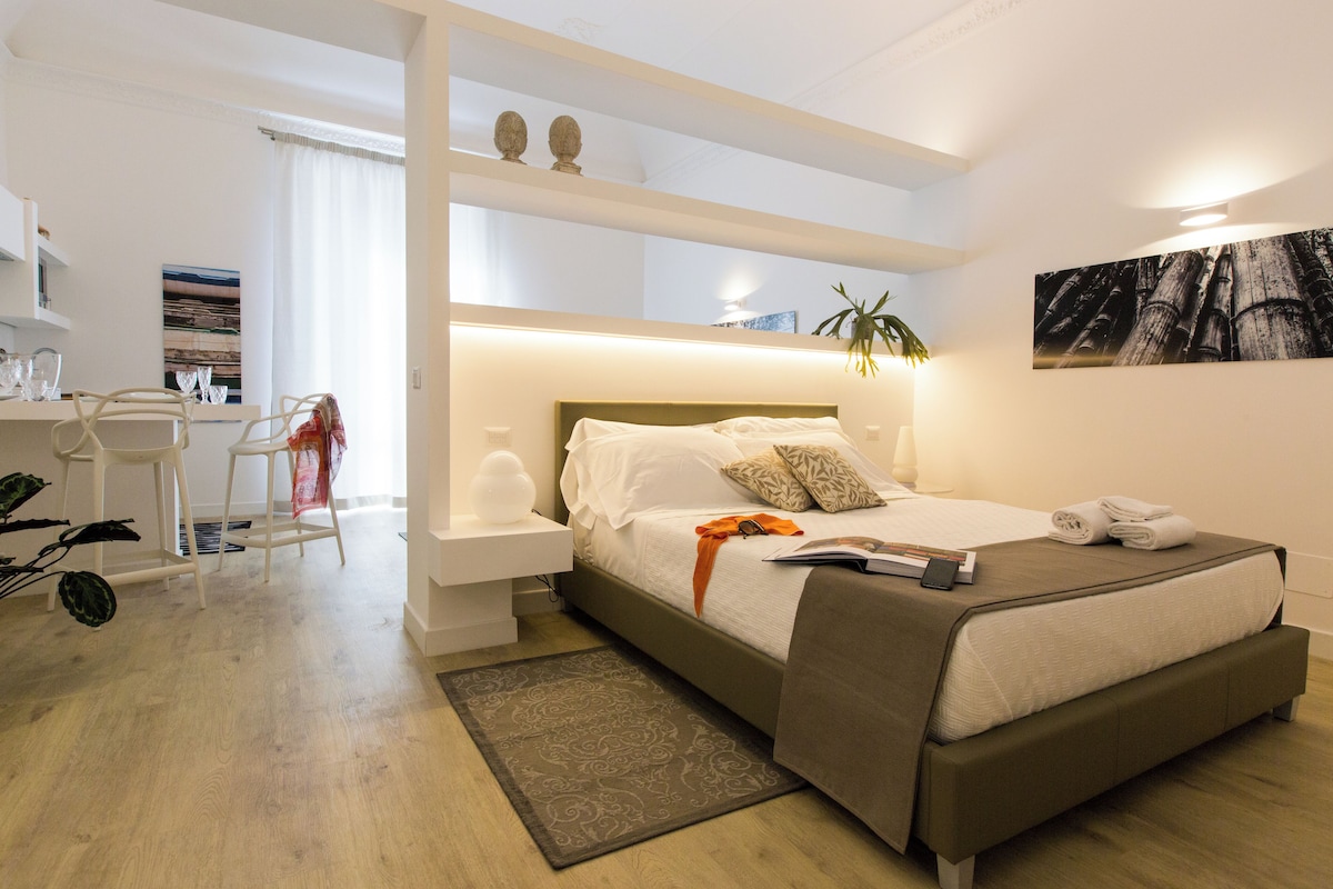A modern bedroom with a bed, bedside tables, a desk, and a chair.