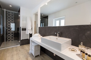 A modern bathroom with a large white sink, dark marble walls, and a glass shower enclosure. - Palermoinsuite Aparthotel (Palermo)