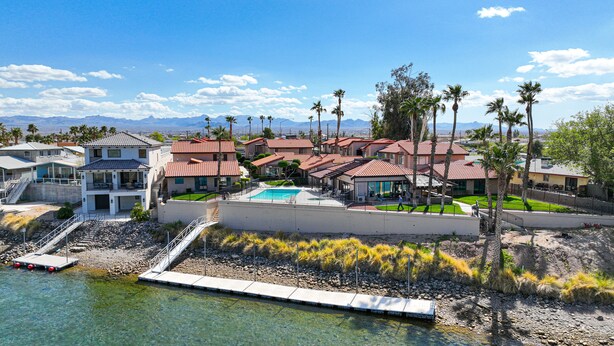 A residential area with houses, a swimming pool, and a dock by a clear water body.