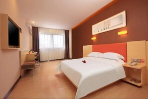 Relax in comfort with a large bed, wooden nightstand, and desk, plus a flat-screen TV and framed artwork.