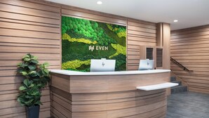 A reception desk with a green wall and the text "IN EVEN". - EVEN Hotel Long Island City - New York by IHG (Long Island City)