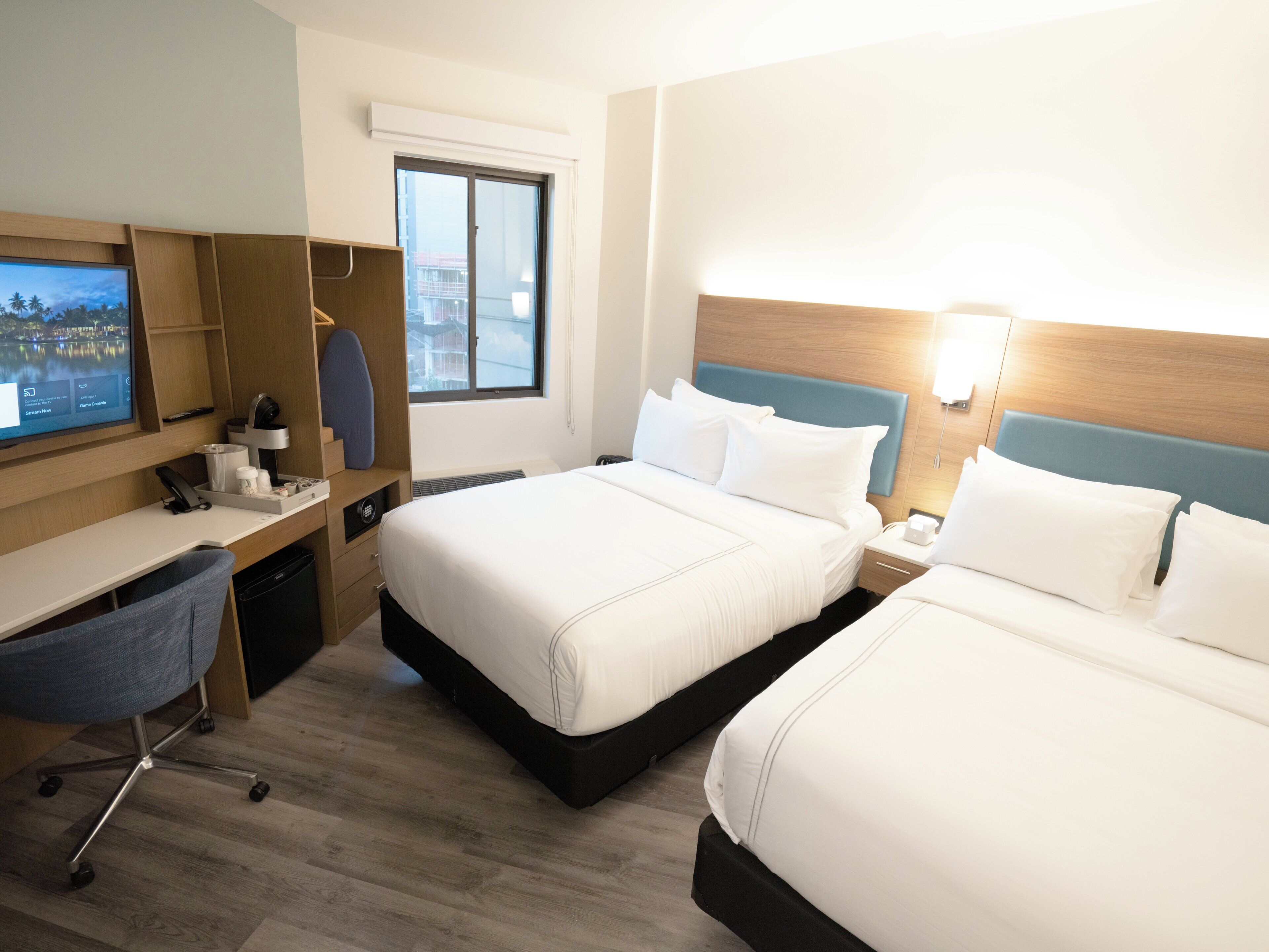 Una habitación de hotel con dos camas, un escritorio, un televisor y una ventana.