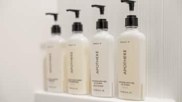 Four bottles of bath gel on a white shelf.