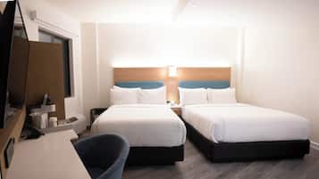 Une chambre d’hôtel avec deux lits, un bureau, une chaise et un téléviseur.