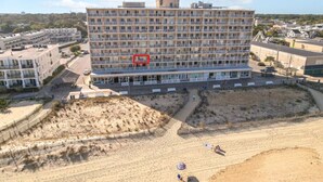A multi-story hotel with balconies, located near a sandy beach area. - Ocean View Escape Studio Condo (Rehoboth Beach)