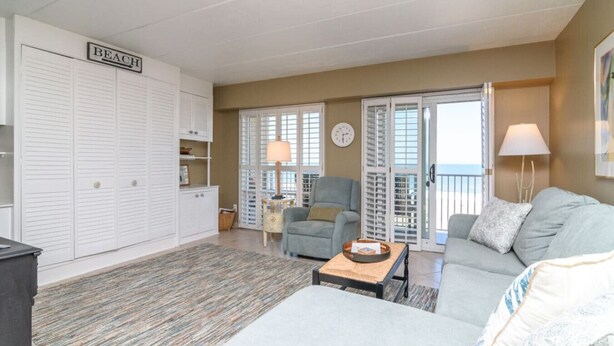 A living room with a sofa, a chair, a coffee table, and a wardrobe labeled 'BEACH'. - Ocean View Escape Studio Condo (Rehoboth Beach)